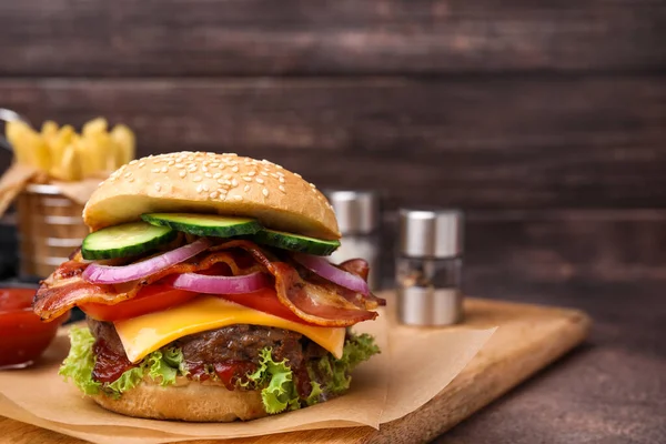 Tasty burger with bacon, vegetables and patty on textured table. Space for text