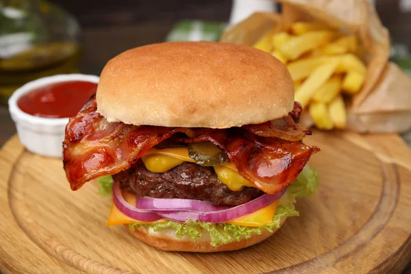 Tasty burger with bacon, vegetables and patty served with french fries and ketchup on wooden board, closeup
