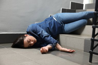 Bilinci yerinde olmayan bir kadın merdivenlerden düştükten sonra yerde yatıyor.