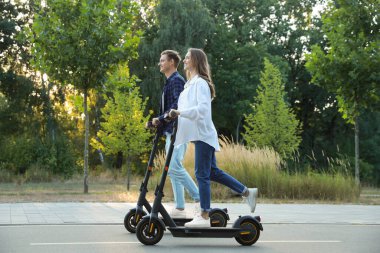 Parkta modern elektrikli scooter kullanan mutlu bir çift.