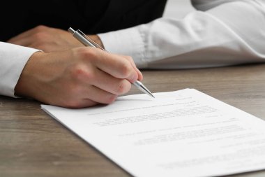 Ahşap masada belge imzalayan adam, yakın plan