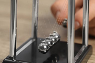 Masada Newton 'un beşiği ile oynayan adam, yakın plan. Enerji korunumunun fizik yasası