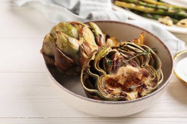 Lezzetli ızgara enginarlı kase beyaz ahşap masada, yakın plan.