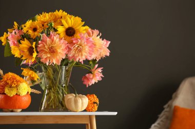 Güz kompozisyonu, güzel çiçekler ve balkabaklarıyla beyaz masada koyu gri arka planda. Metin için boşluk
