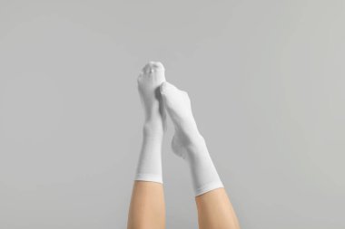 Açık gri arka planda şık beyaz çoraplı kadın, yakın plan.