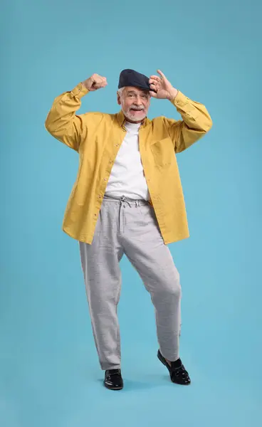 stock image Happy senior man dancing on light blue background