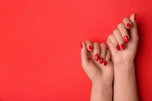 Woman with gel polish on nails against red background, closeup. Space for text