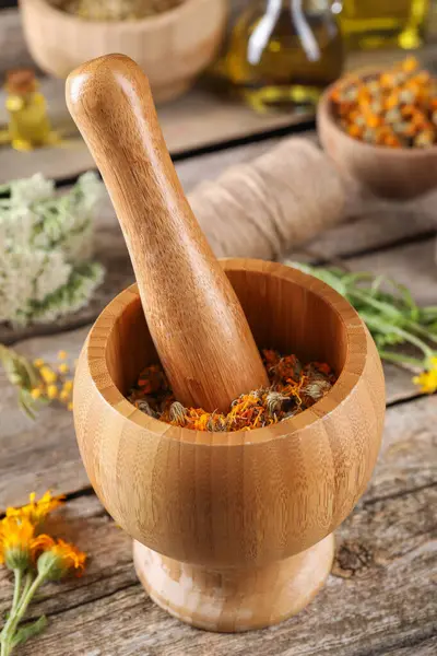 Mortar with pestle and calendula flowers on wooden table. Medicinal herbs