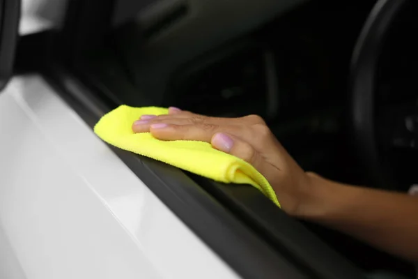 Woman cleaning car door with rag, closeup
