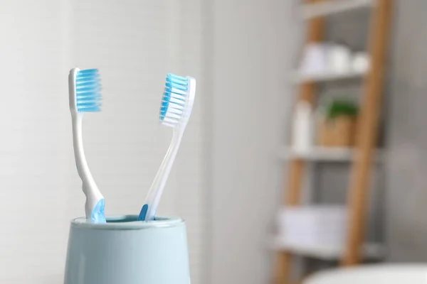 Plastic toothbrushes in holder on blurred background, closeup. Space for text