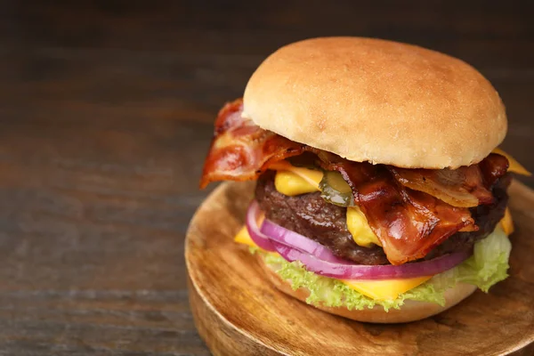 Tasty burger with bacon, vegetables and patty on wooden table, closeup. Space for text