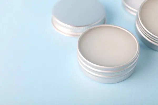 Lip balms on light blue background, closeup. Space for text