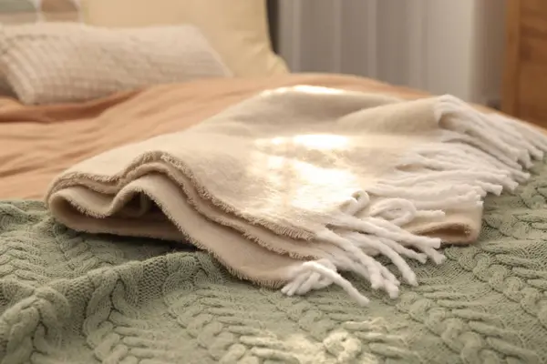 Soft blankets on bed indoors, closeup. Home textile