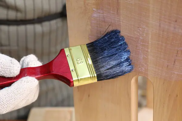 Man varnishing wooden step stool, closeup view