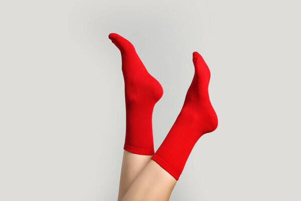 Woman in stylish red socks on light grey background, closeup