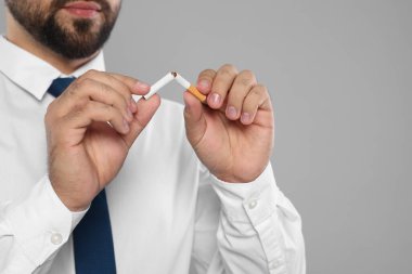 Sigara içmeyi bırak. Açık gri arka planda sigara kıran adam, yakın plan. Metin için boşluk
