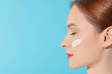 Yüzünde açık mavi arka planda güneş kremi olan genç ve güzel bir kadın. Yakın plan. Metin için boşluk