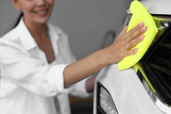 Woman cleaning car headlight with rag, closeup view