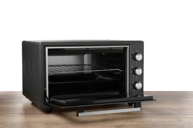 Ahşap masada beyaz zemine karşı bir elektrikli fırın.