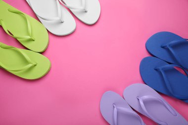 Pembe arka planda farklı tarz parmak arası terlikler, düz yatış. Metin için boşluk