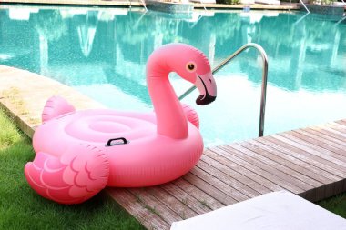 Lüks bir tatil köyünde yüzme havuzunun yanındaki tahta güvertede flamingo şeklinde süzül.