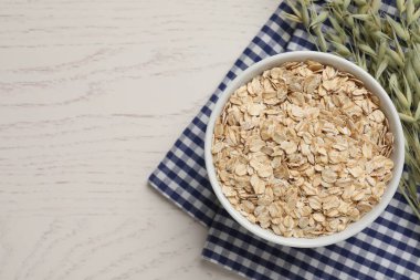 Bir kase yulaf ezmesi ve beyaz ahşap masa üzerinde çiçekli dallar. Metin için boşluk