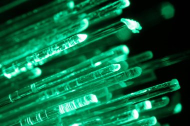 Optik fiber iplikler siyah arkaplan üzerinde yeşil ışık iletiyor, makro görünüm