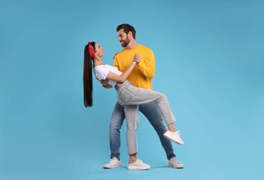 Mutlu çift açık mavi arka planda dans ediyor.