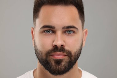 Açık gri arka planda genç bir adamın portresi, yakın plan.