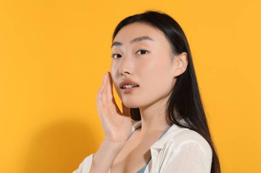 Turuncu arka planda makyajlı güzel bir genç kadın. Metin için boşluk