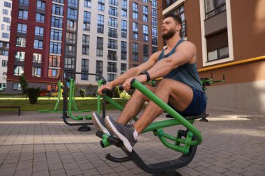 Spor salonunda kürek çekme makinesinde çalışan bir adam.