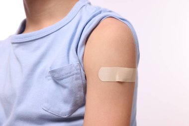 Beyaz arka plan aşısı üstüne koluna alçı yapıştıran çocuk, yakın plan.