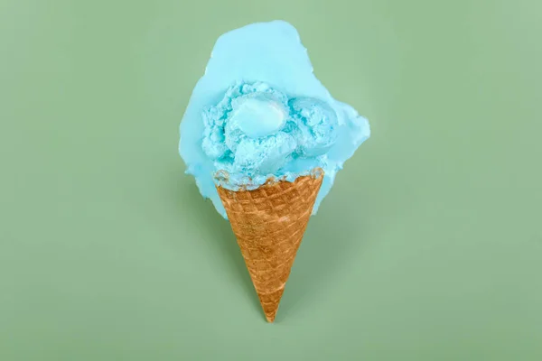 Melted ice cream and wafer cone on green background, top view