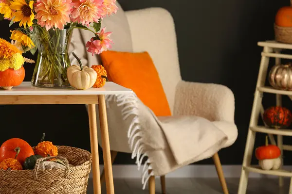 Room decorated with pumpkins and bright flowers, space for text. Autumn vibes