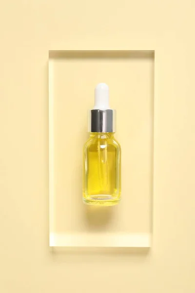 Bottle of cosmetic serum on beige background, top view