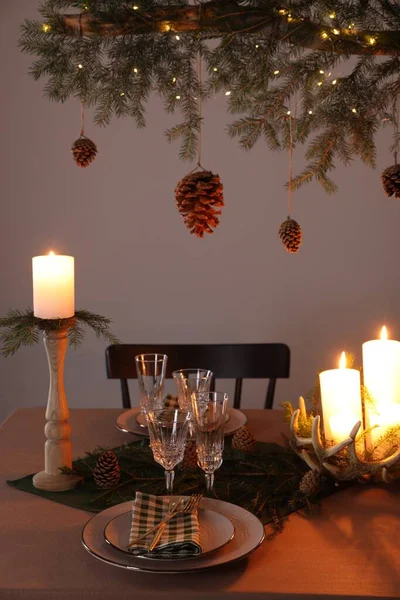Weihnachtsfeier Zapfen Hängen Von Tannenzweig Über Tisch Mit Brennenden Kerzen — Stockfoto