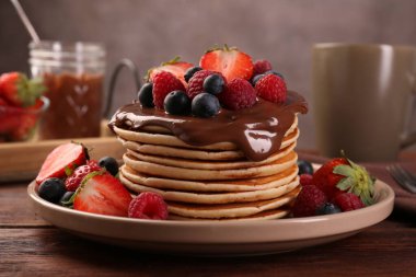 Tahta masaya serilmiş taze böğürtlenli ve çikolatalı leziz krepler, yakın plan.