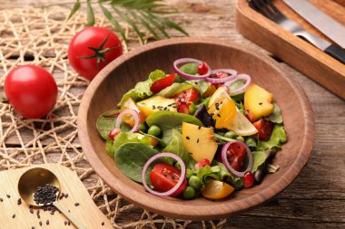 Ahşap masada servis edilen şeftalili, yeşil bezelyeli ve sebzeli lezzetli salata.