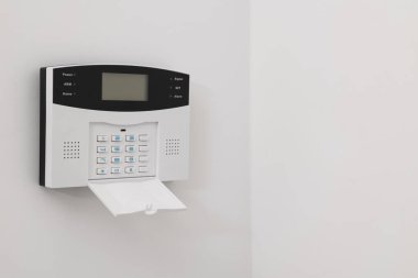 Home security alarm system on white wall indoors, space for text clipart