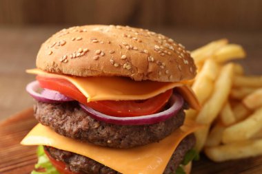 Köfteli lezzetli hamburger, ahşap masada peynir ve sebzeler, yakın plan.