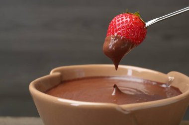 Çilekli ve çatallı, fondüsünün üstünde erimiş çikolata, yakın plan. Metin için boşluk
