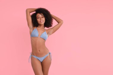 Pembe arka planda şık bikinili güzel kadın, mesaj için yer var.