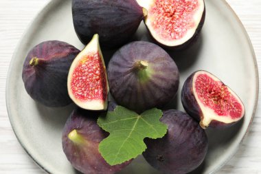 Beyaz ahşap masa üzerinde yaprak ile tam ve olgun incir kesim üst görünüm