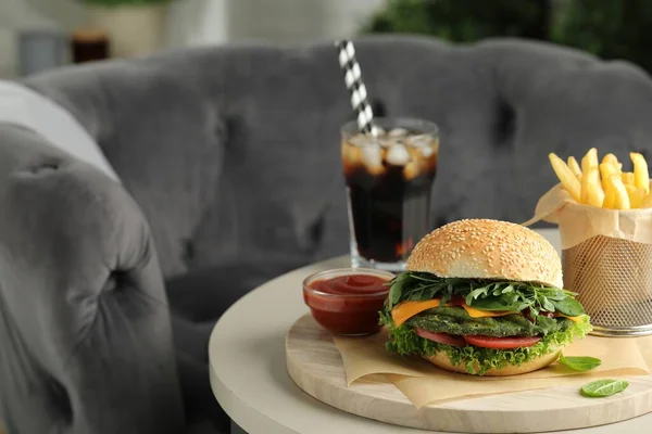 Tasty vegetarian burger served with french fries and soda drink on white table, space for text