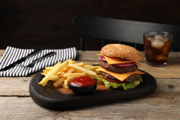 Delicious burger with meat cutlets, french fries and sauce on wooden table