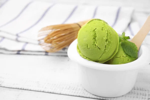 Tasty matcha ice cream in bowl on white wooden table. Space for text