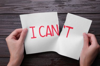 Motivasyon konsepti. Bir kadın bunu yapabilir miyim? Ahşap masadaki kağıdı yırtarak yapamam.