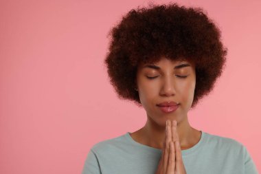 Elleri sımsıkı bağlı bir kadın pembe arka planda Tanrı 'ya dua ediyor. Metin için boşluk