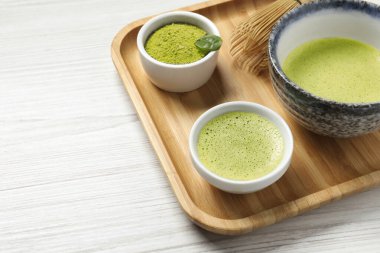 Taze kibrit çayı, bambu çırpısı ve beyaz ahşap masada yeşil toz, yakın plan. Metin için boşluk