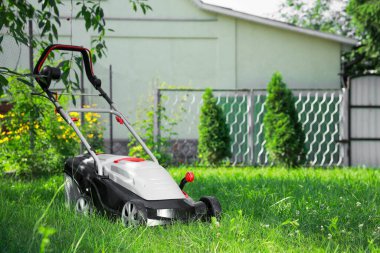 Bahçedeki yeşil çimlerin üzerinde çim biçme makinesi, metin için yer